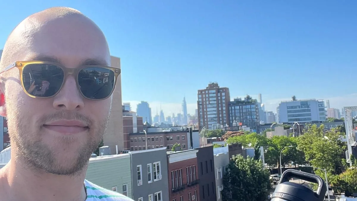 Hunter Watkin on a New York rooftop, the Manhattan skyline behind.