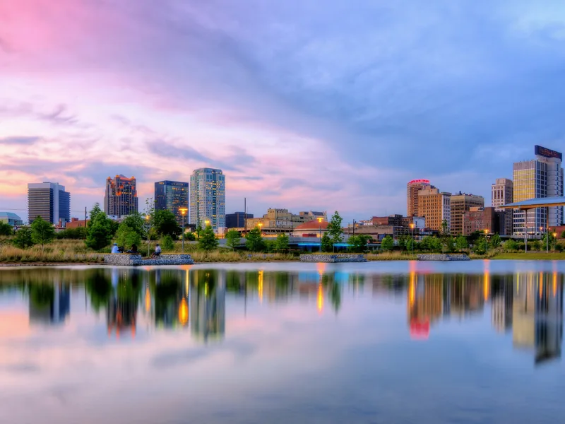 Birmingham’s downtown skyline reflected in the lake at Railroad Park at dusk.