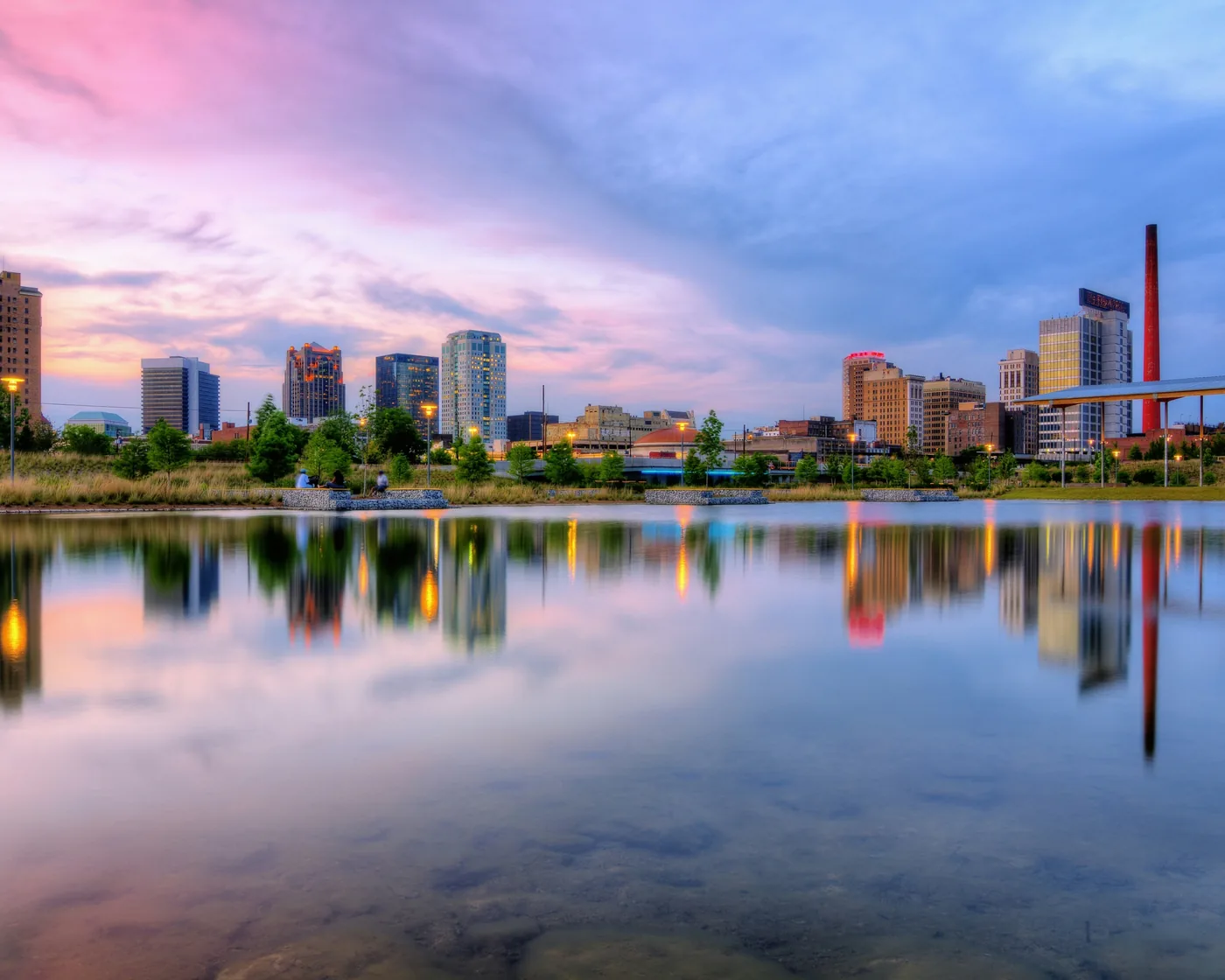 Birmingham’s downtown skyline reflected in the lake at Railroad Park at dusk.