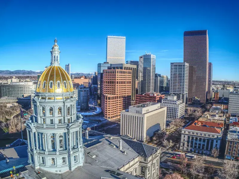 The gold dome of the Colorado State Capitol in front of downtown Denver’s towers.
