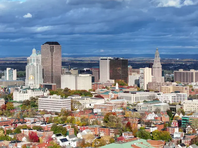 Hartford’s downtown towers, the Travelers Tower and the gold dome of the State Capitol above red-brick streets in autumn.
