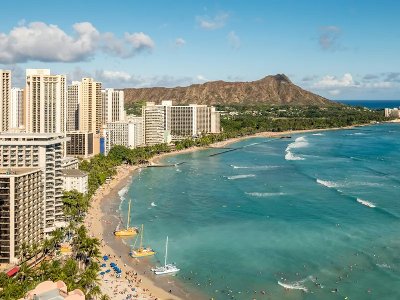 Waikīkī Beach curving toward Diamond Head, with hotel towers along the shore in Honolulu.