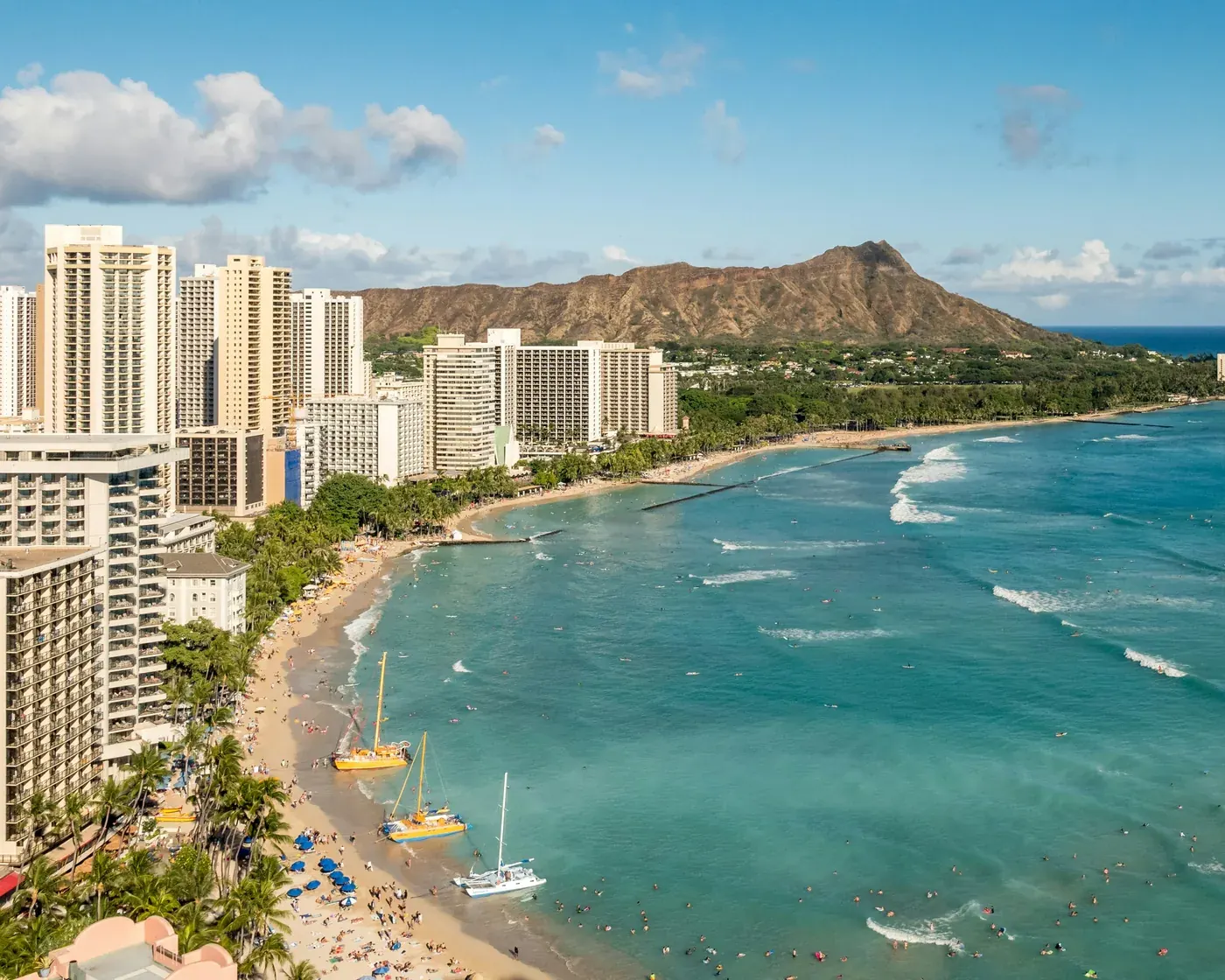 Waikīkī Beach curving toward Diamond Head, with hotel towers along the shore in Honolulu.