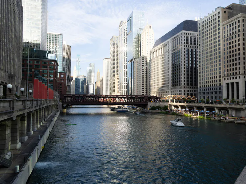 The Chicago River running between downtown towers, seen from Wolf Point, with a bridge and boats on the water.