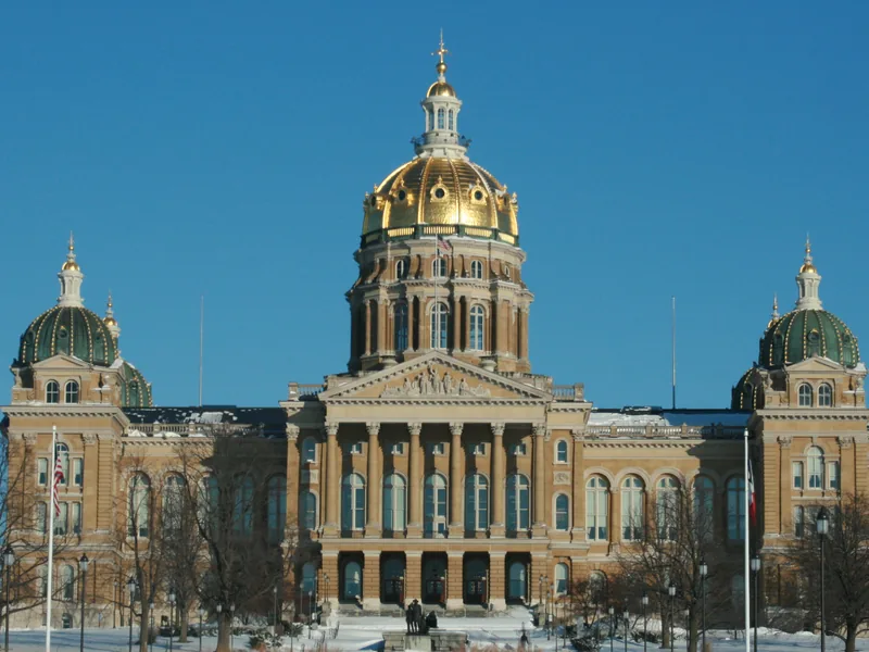 The gold dome of the Iowa State Capitol in Des Moines under a clear winter sky.