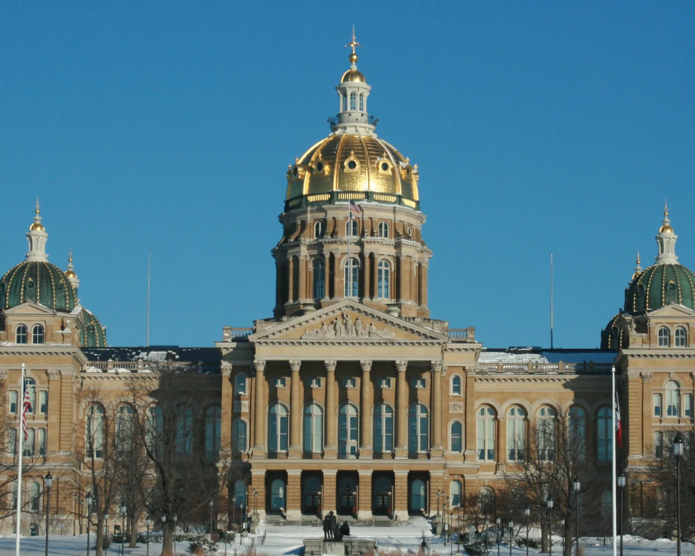 The gold dome of the Iowa State Capitol in Des Moines under a clear winter sky.