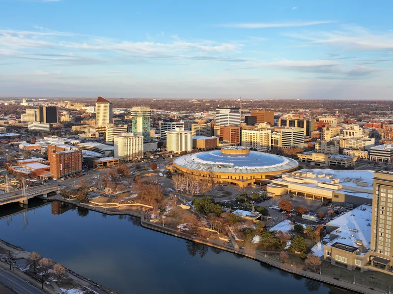 Downtown Wichita in late-afternoon light, with the round Century II hall beside the Arkansas River.