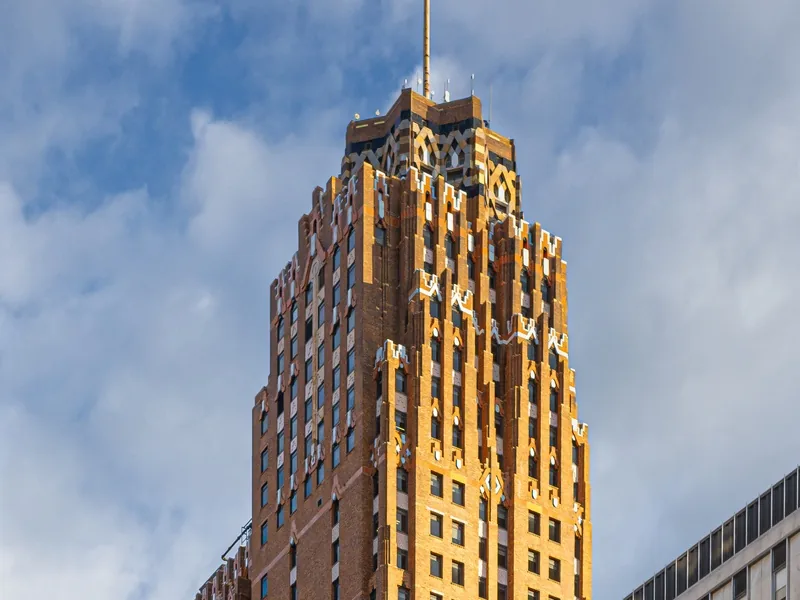 The orange brick and tile crown of the Guardian Building in downtown Detroit, lit by low sun against a cloudy sky.