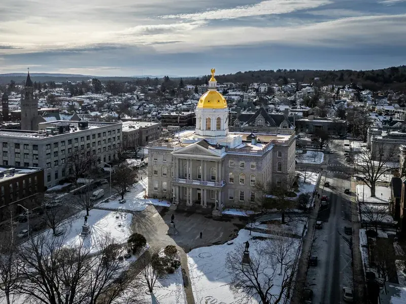 The gold-domed New Hampshire State House in Concord, seen from above on a bright winter afternoon with snow on the grounds.