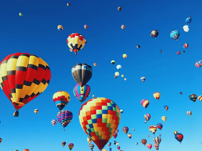 Dozens of hot air balloons rising into a clear blue sky over Albuquerque.