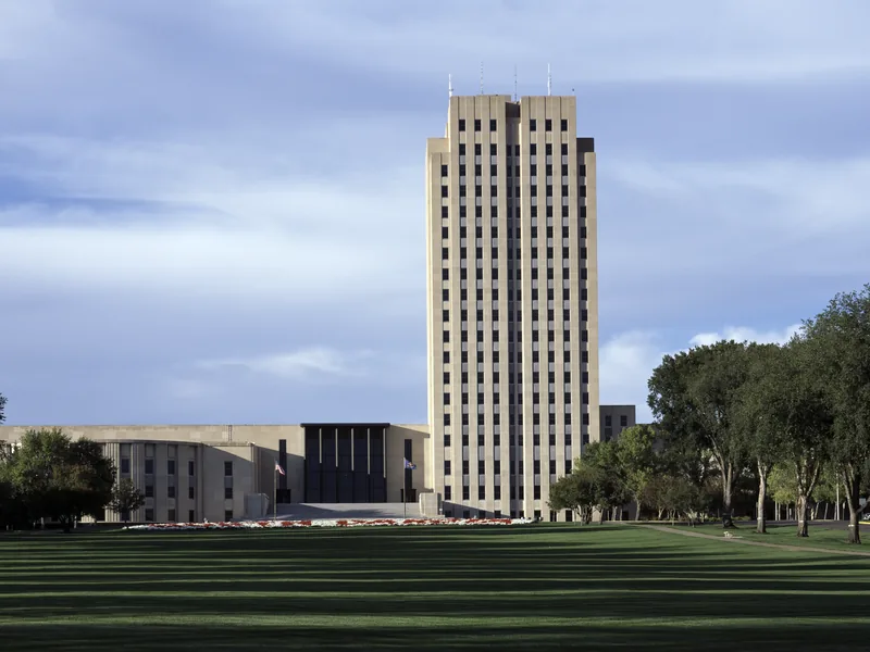 The North Dakota State Capitol tower in Bismarck above its long lawn in late afternoon light.