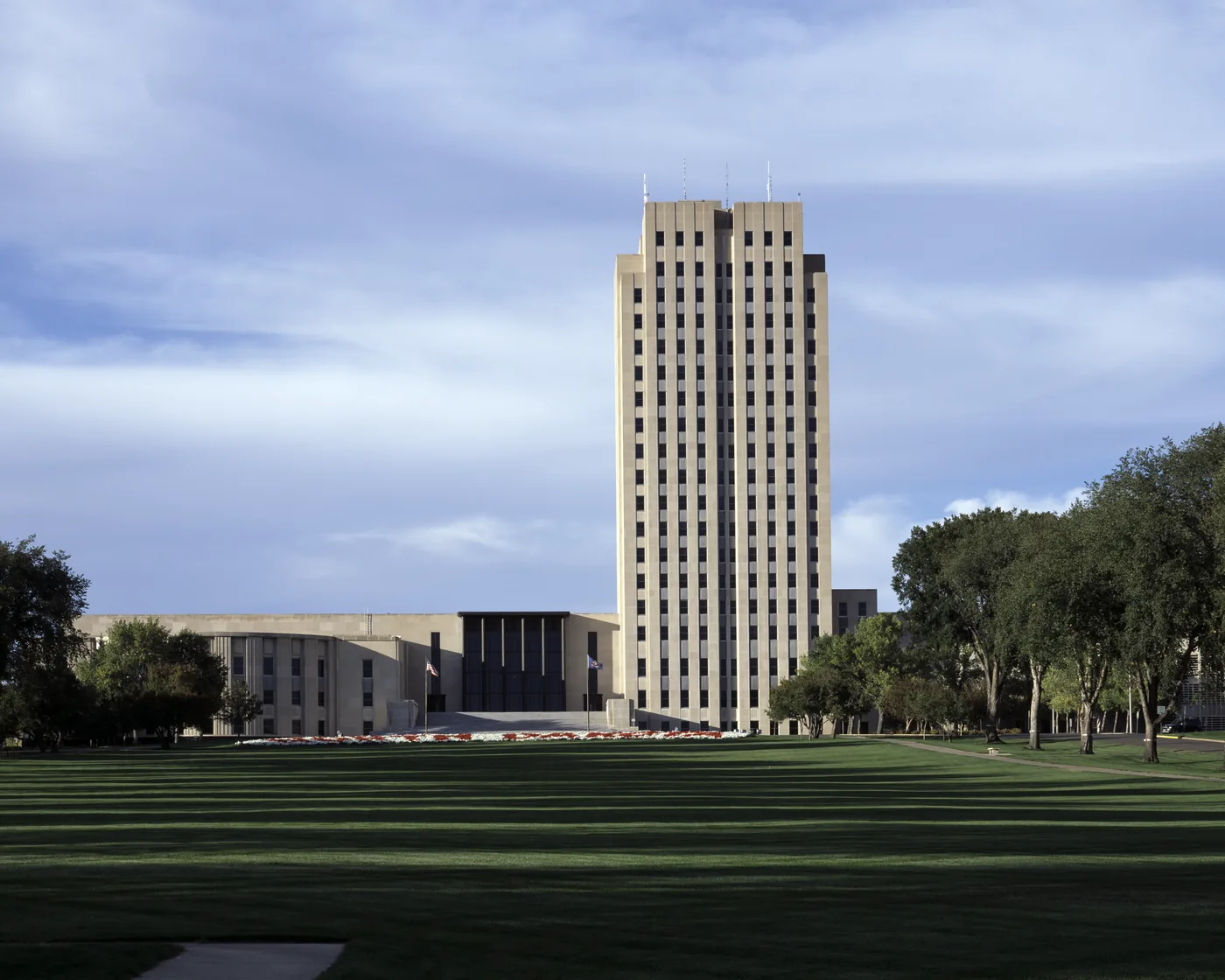 The North Dakota State Capitol tower in Bismarck above its long lawn in late afternoon light.