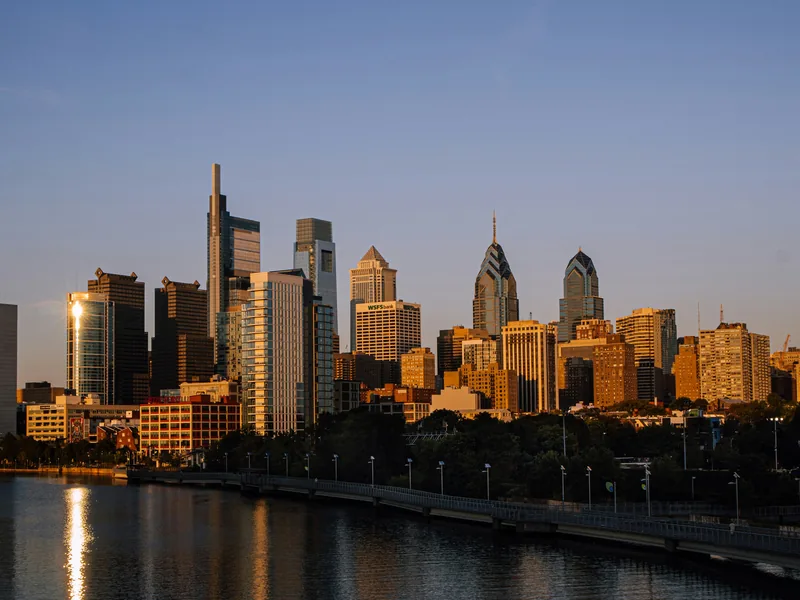 Center City Philadelphia’s skyline in golden-hour light above the Schuylkill River and the Schuylkill River Trail boardwalk.
