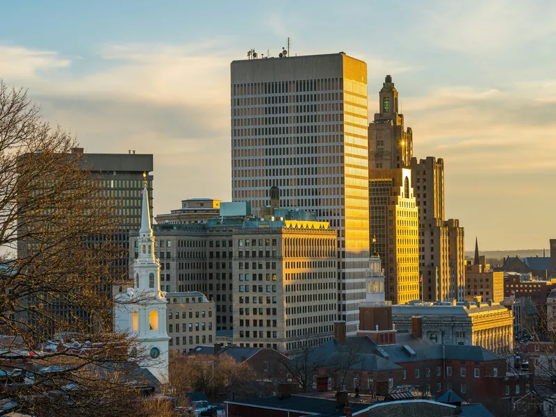 Downtown Providence in late-afternoon light, with the white steeple of the First Baptist Meeting House in front of the Industrial Trust Building, from Prospect Terrace Park.