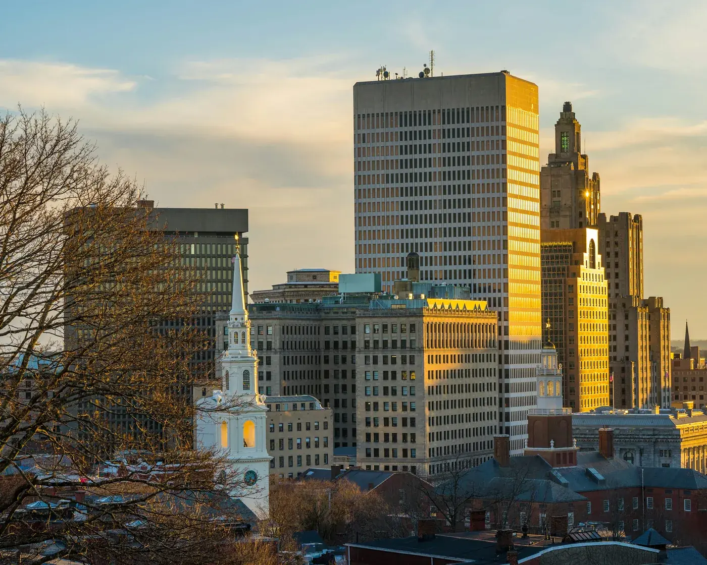 Downtown Providence in late-afternoon light, with the white steeple of the First Baptist Meeting House in front of the Industrial Trust Building, from Prospect Terrace Park.