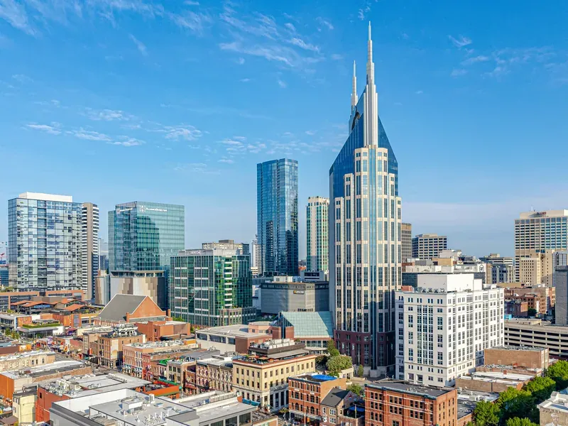 Downtown Nashville under a clear blue sky, with a tall twin-spired tower rising above the brick blocks near Lower Broadway.