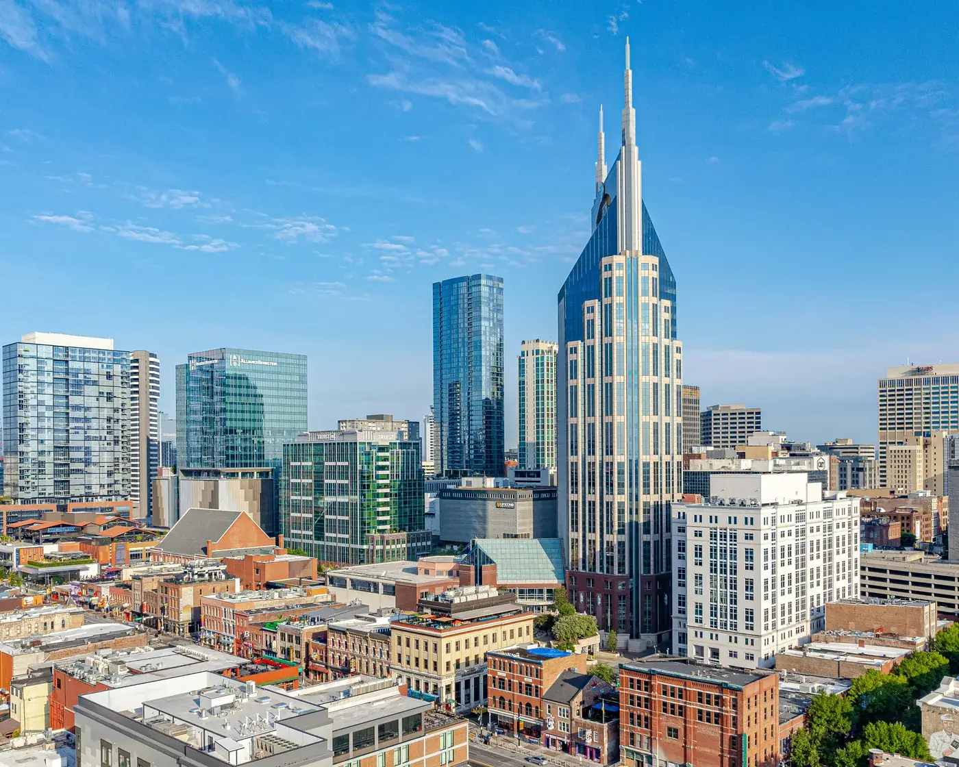 Downtown Nashville under a clear blue sky, with a tall twin-spired tower rising above the brick blocks near Lower Broadway.