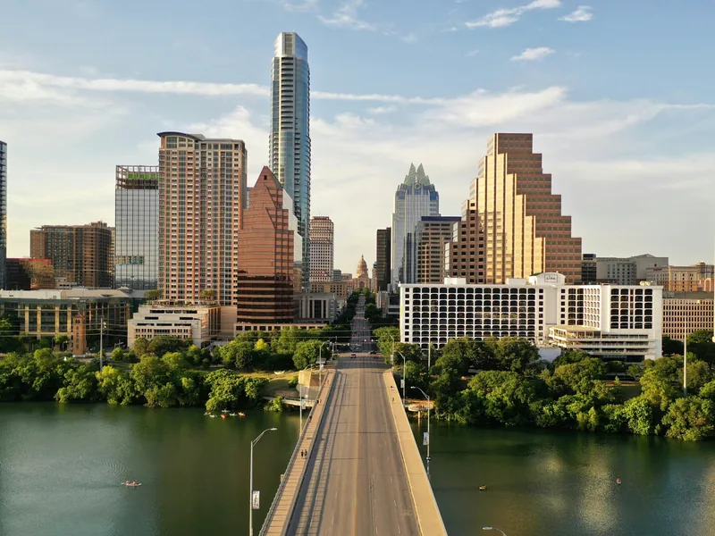Downtown Austin in late-afternoon sun, looking up Congress Avenue from the Lady Bird Lake bridge to the Texas State Capitol.