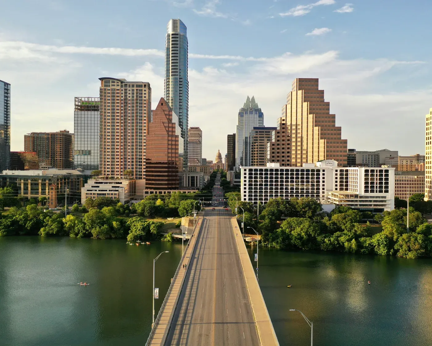 Downtown Austin in late-afternoon sun, looking up Congress Avenue from the Lady Bird Lake bridge to the Texas State Capitol.