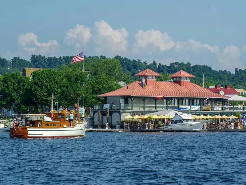 The Burlington Community Boathouse on Lake Champlain on a summer day, with a classic wooden motor yacht passing.